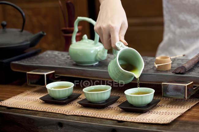 Gros plan de la main féminine versant du thé dans des tasses à thé — Photo de stock