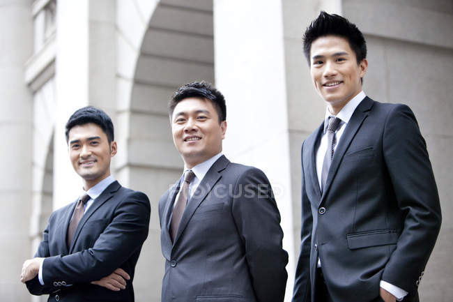 Chinese business team standing in front of building — Stock Photo