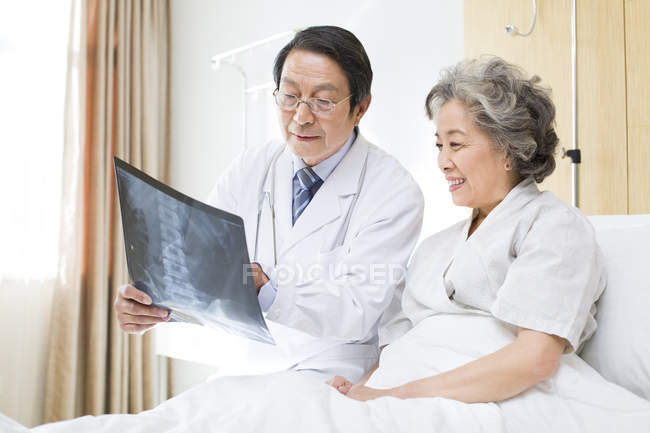 Médico chinês mostrando imagem de raio-X para paciente — Fotografia de Stock