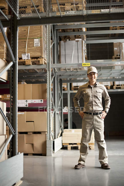Male Chinese warehouse worker standing with hands on hips — Stock Photo