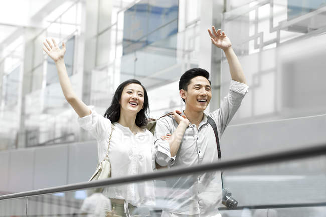 Chinese couple waving on subway station escalator — Stock Photo