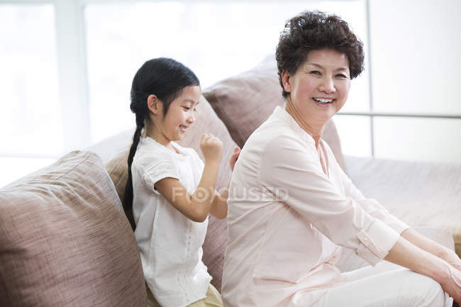 Chinese girl massaging grandmother back — Stock Photo