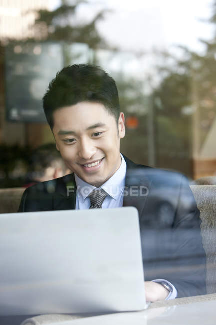 Китайский бизнесмен использует ноутбук в кафе — стоковое фото