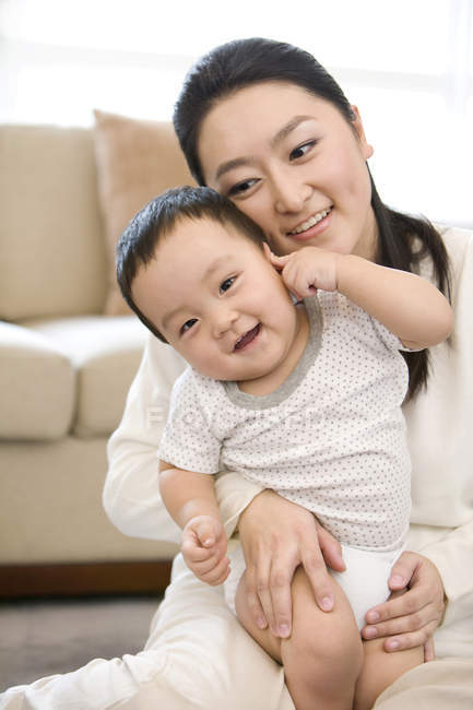 Китайська жінка, що сидить і проведення дитини на колінах — стокове фото