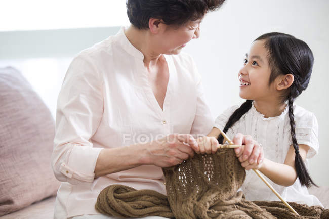 Chinese grandmother and granddaughter knitting in living room — Stock Photo