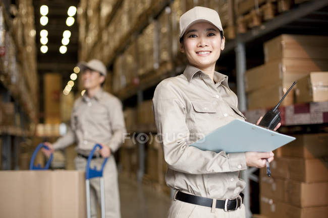 Male and female Chinese workers with walkie-talkie and clipboard — Stock Photo