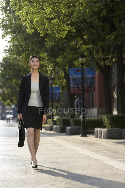 Femme chinoise avec mallette marchant dans la rue — Photo de stock