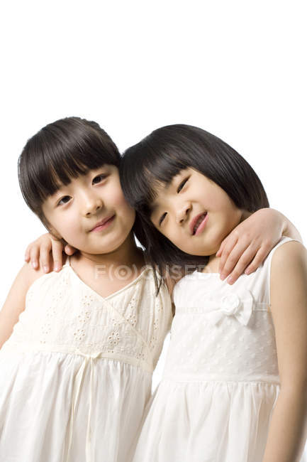 Little Chinese girls embracing and looking in camera on white background — Stock Photo