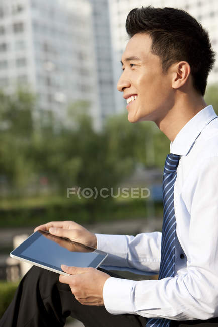 Homme d'affaires chinois assis avec tablette numérique dans le parc — Photo de stock
