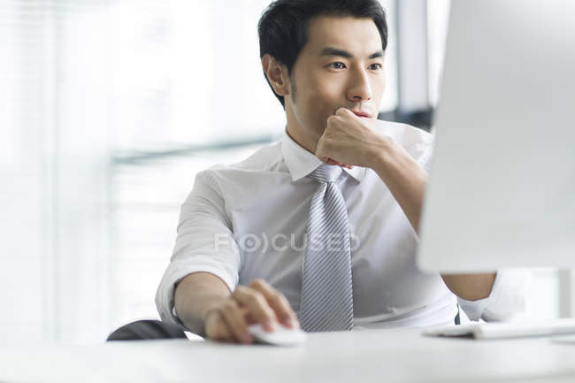 Homme d'affaires chinois utilisant un ordinateur au bureau — Photo de stock