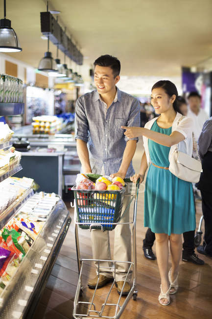 Chinese couple shopping in supermarket with cart — Stock Photo