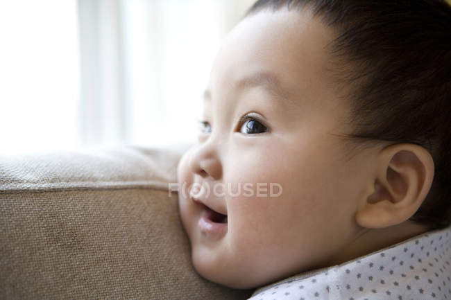 Chinese baby boy leaning on sofa back, close-up — Stock Photo