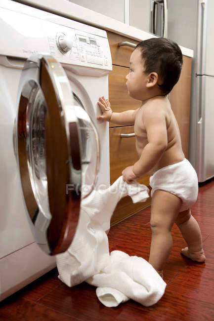 Bebê chinês colocando roupa na máquina de lavar roupa — Fotografia de Stock