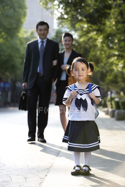 Chinese parents walking with schoolgirl on street — Stock Photo