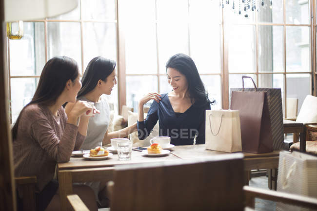 Китайська жінка, демонструючи новий одяг жіночий друзям в кафе — стокове фото