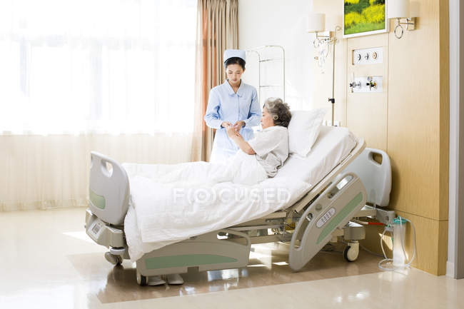 Enfermeira chinesa cuidando de mulher idosa no hospital — Fotografia de Stock