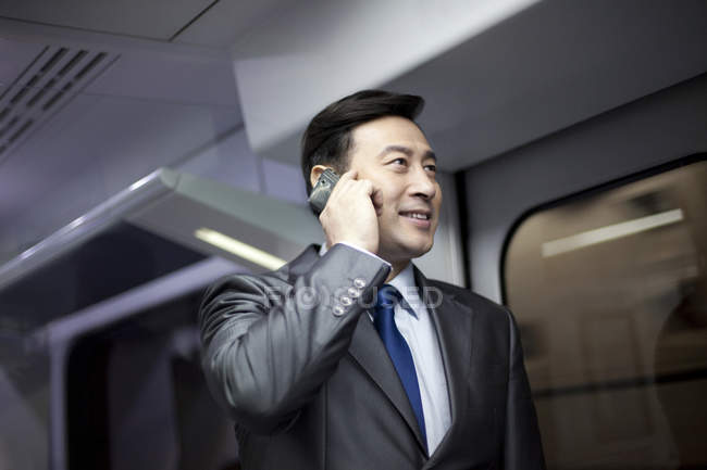 Homem de negócios chinês falando ao telefone no metrô — Fotografia de Stock