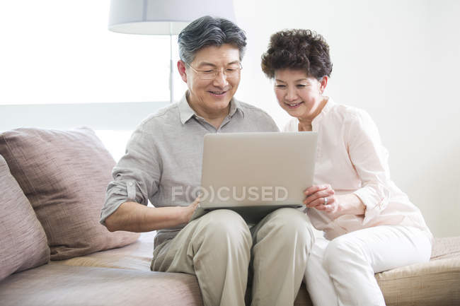 Senior chinesisches Paar mit Laptop auf Sofa — Stockfoto