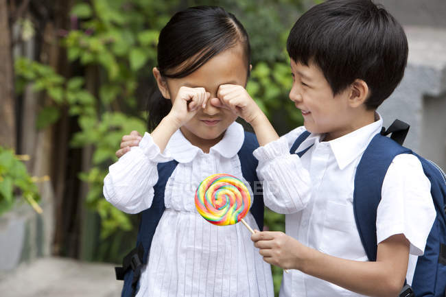 Ragazzo cinese consolante piangendo ragazza con lecca-lecca — Foto stock