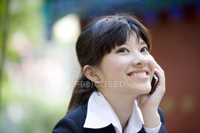 Empresaria china hablando por teléfono y sonriendo en la calle - foto de stock