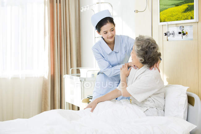 Chinesisch krankenschwester giving schultermassage bis senior frau — Stockfoto