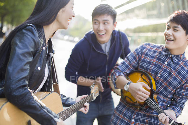 Chinese friends playing musical instruments on street — Stock Photo