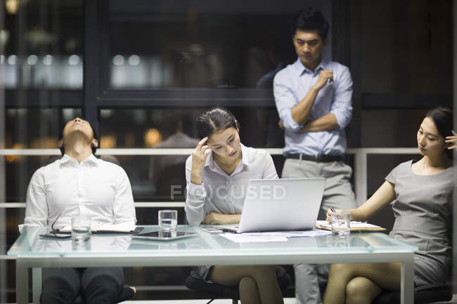 Equipo de negocios chino cansado sentado en la reunión - foto de stock