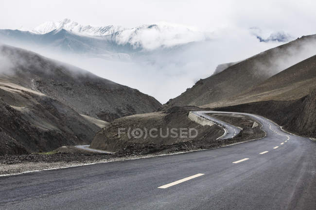 Camino en las montañas con curva de horquilla en el Tíbet, China - foto de stock