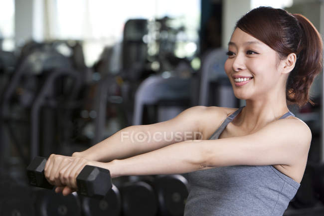Китаянка поднимает гантели в спортзале — стоковое фото