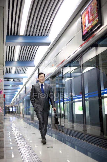 Homme d'affaires chinois avec mallette marchant à la station de métro — Photo de stock