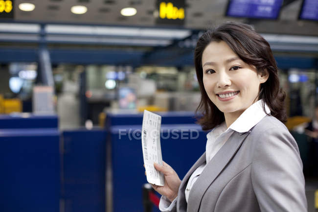 Chinesische Geschäftsfrau hält Ticket im Flughafen — Stockfoto