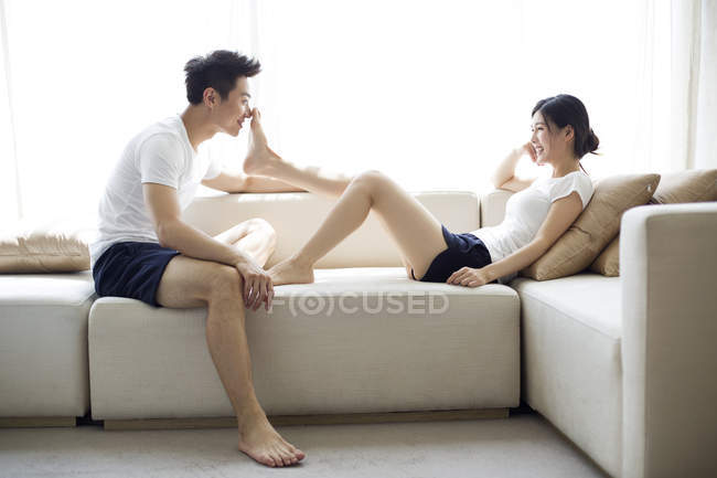 Young Chinese couple relaxing on sofa at home — Stock Photo