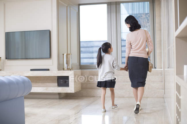 Mother and daughter walking to door and holding hands — Stock Photo