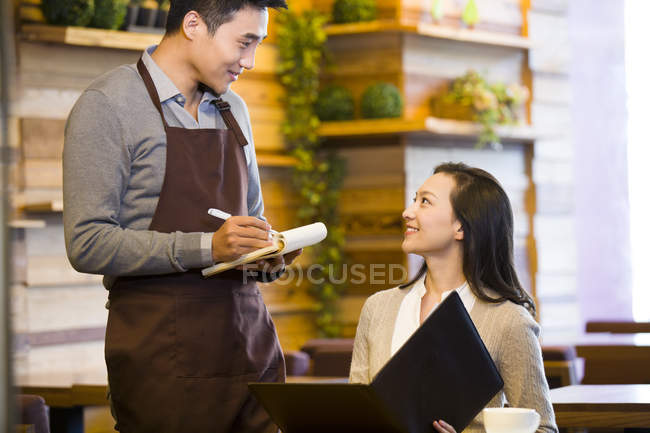 Chinese waiter taking order from woman at restaurant — Stock Photo
