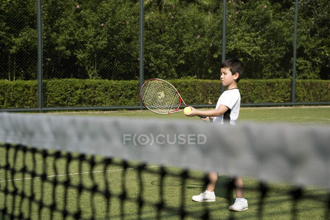 Маленький китайский мальчик играет в теннис при дворе — стоковое фото