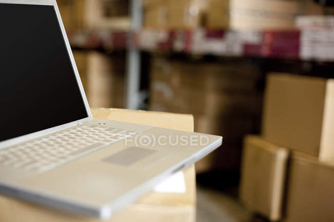Laptop em caixa de papelão no armazém — Fotografia de Stock