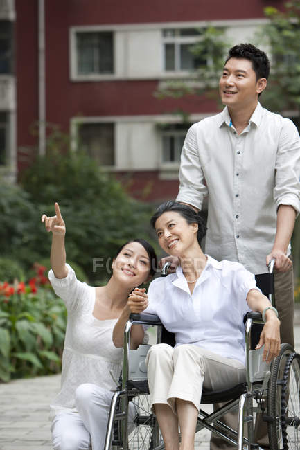 Chinese couple with senior woman in wheelchair on street — Stock Photo