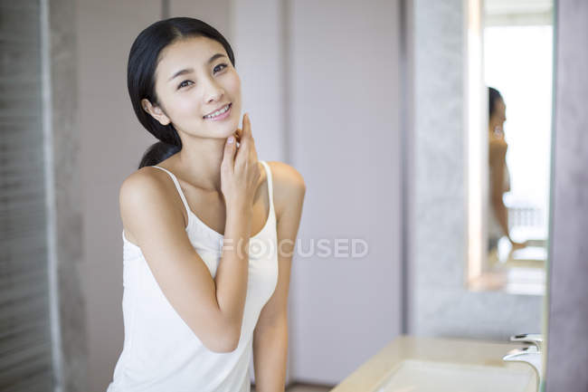 Mulher chinesa aplicando hidratante na pele — Fotografia de Stock