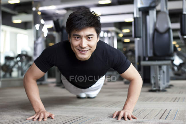 Chinese man doing push ups at gym — Stock Photo