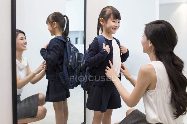 Mère chinoise ajustant uniforme écolière le matin — Photo de stock