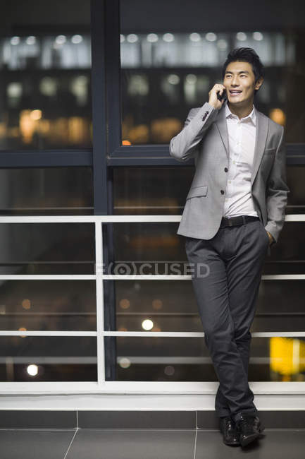 Hombre de negocios chino hablando por teléfono en el edificio de oficinas - foto de stock