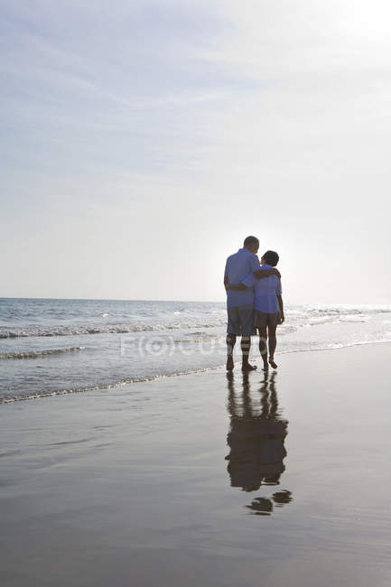 Senior couple walking along sea beach — Stock Photo