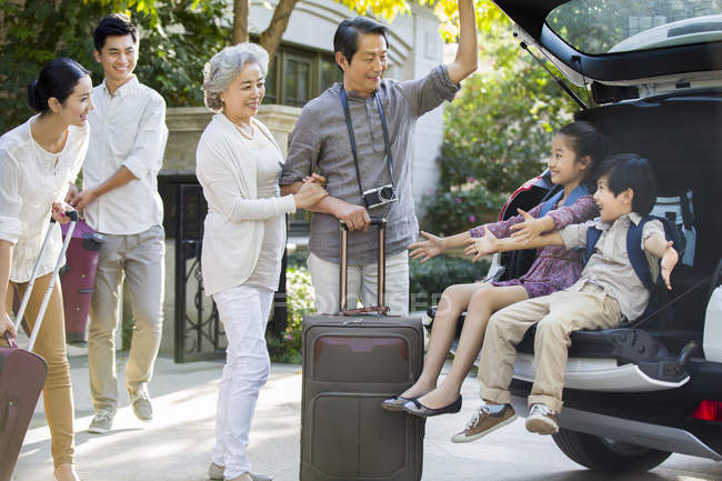 Китайская семья из нескольких поколений упаковывает вещи для поездки на машине — стоковое фото