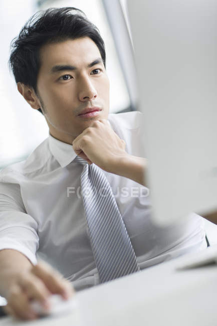 Empresário chinês pensivo usando computador no escritório — Fotografia de Stock