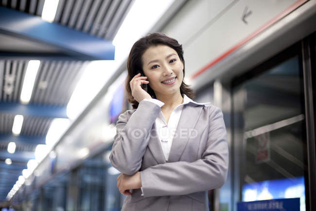 Chinese businesswoman talking on phone at subway platform — Stock Photo