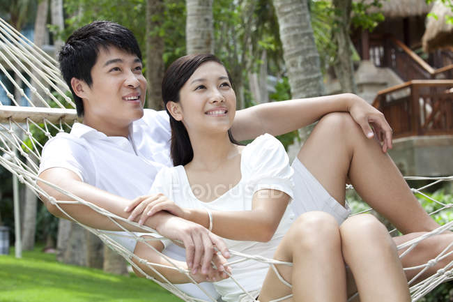 Chinese couple relaxing in hammock on vacation — Stock Photo