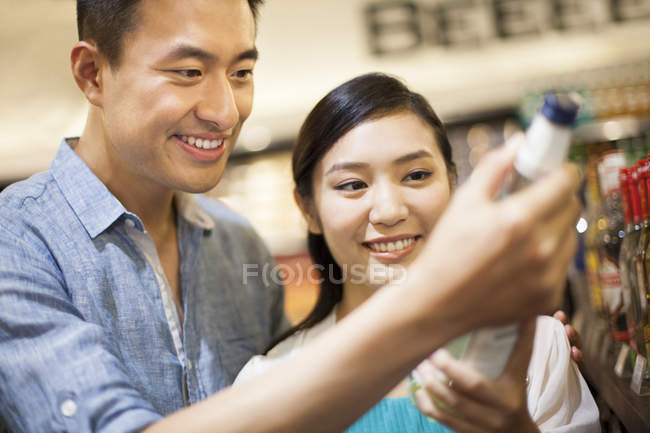 Chinese couple buying wine in supermarket — Stock Photo