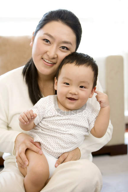Mujer china sentada y sosteniendo al bebé en el regazo - foto de stock