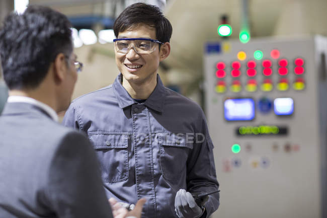 Businessman and engineer talking at industrial factory — Stock Photo