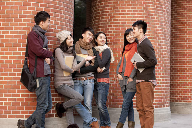 Chinese college students chatting in front of university building — Stock Photo